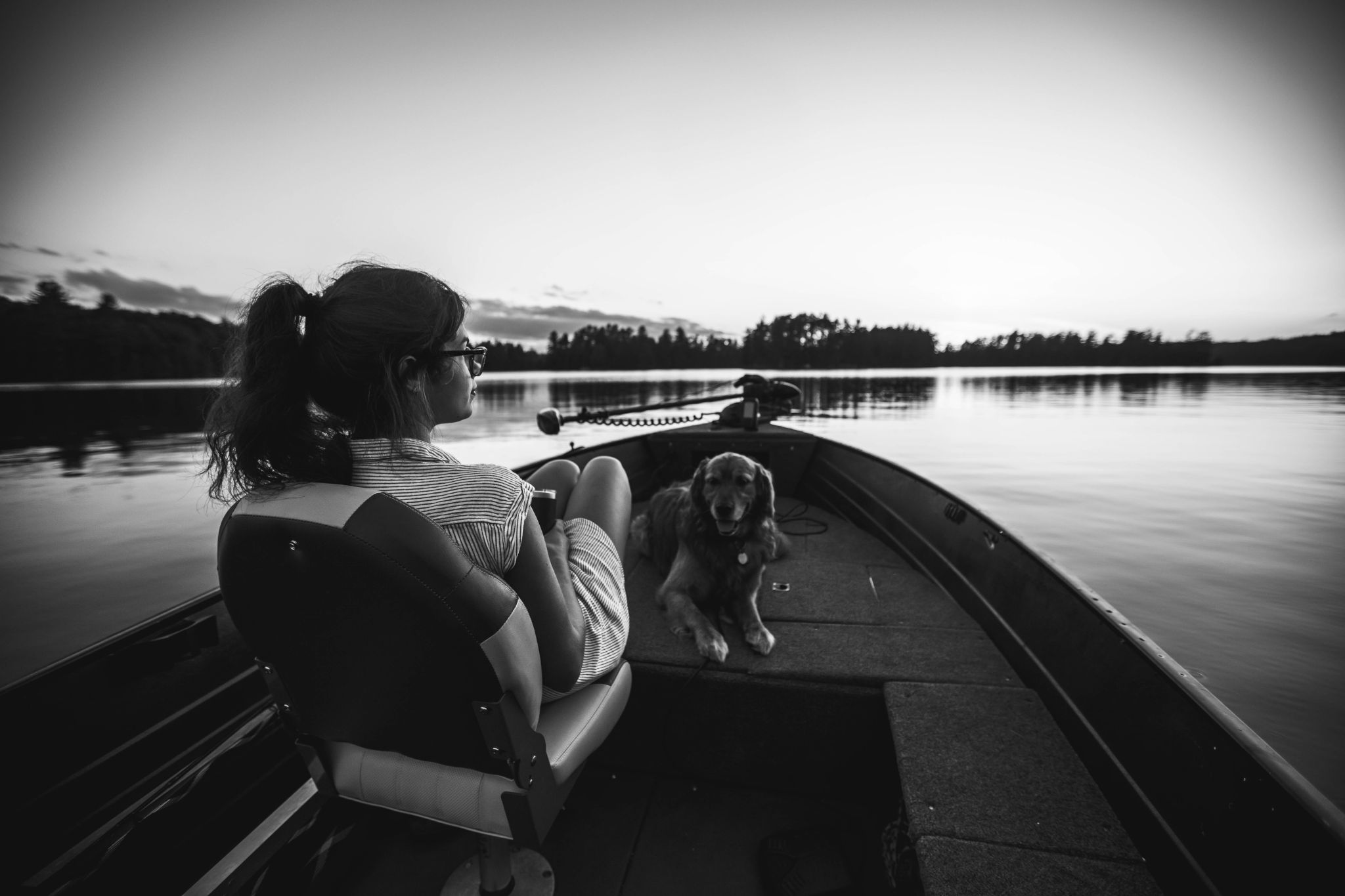 A picture of a dog with a girl sitting in a boat